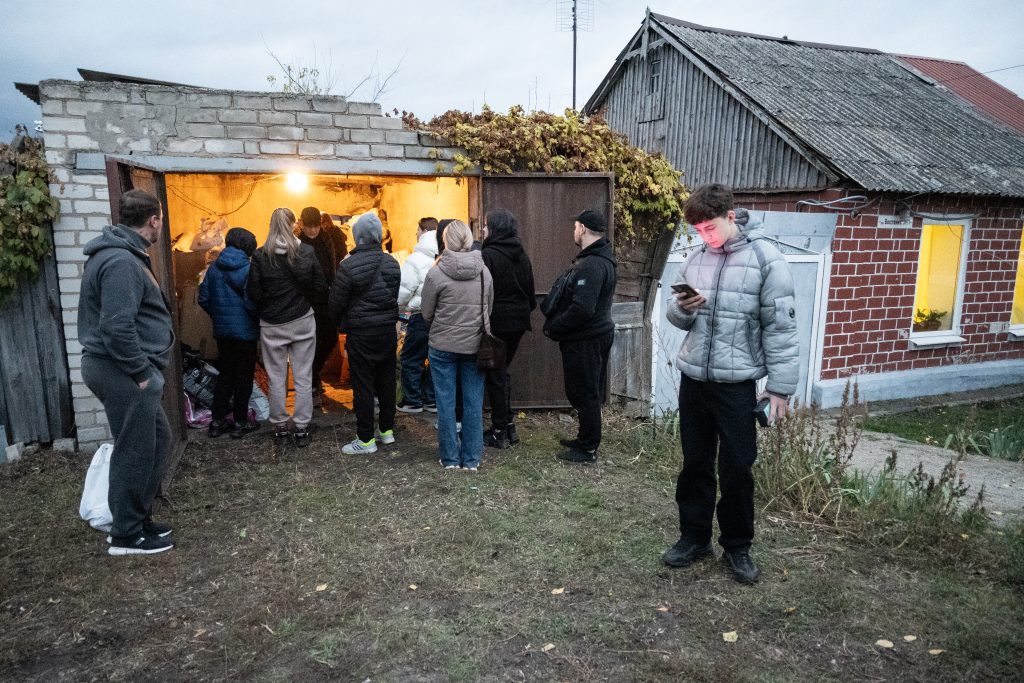 A group of people wait at the door the shed for supplies.