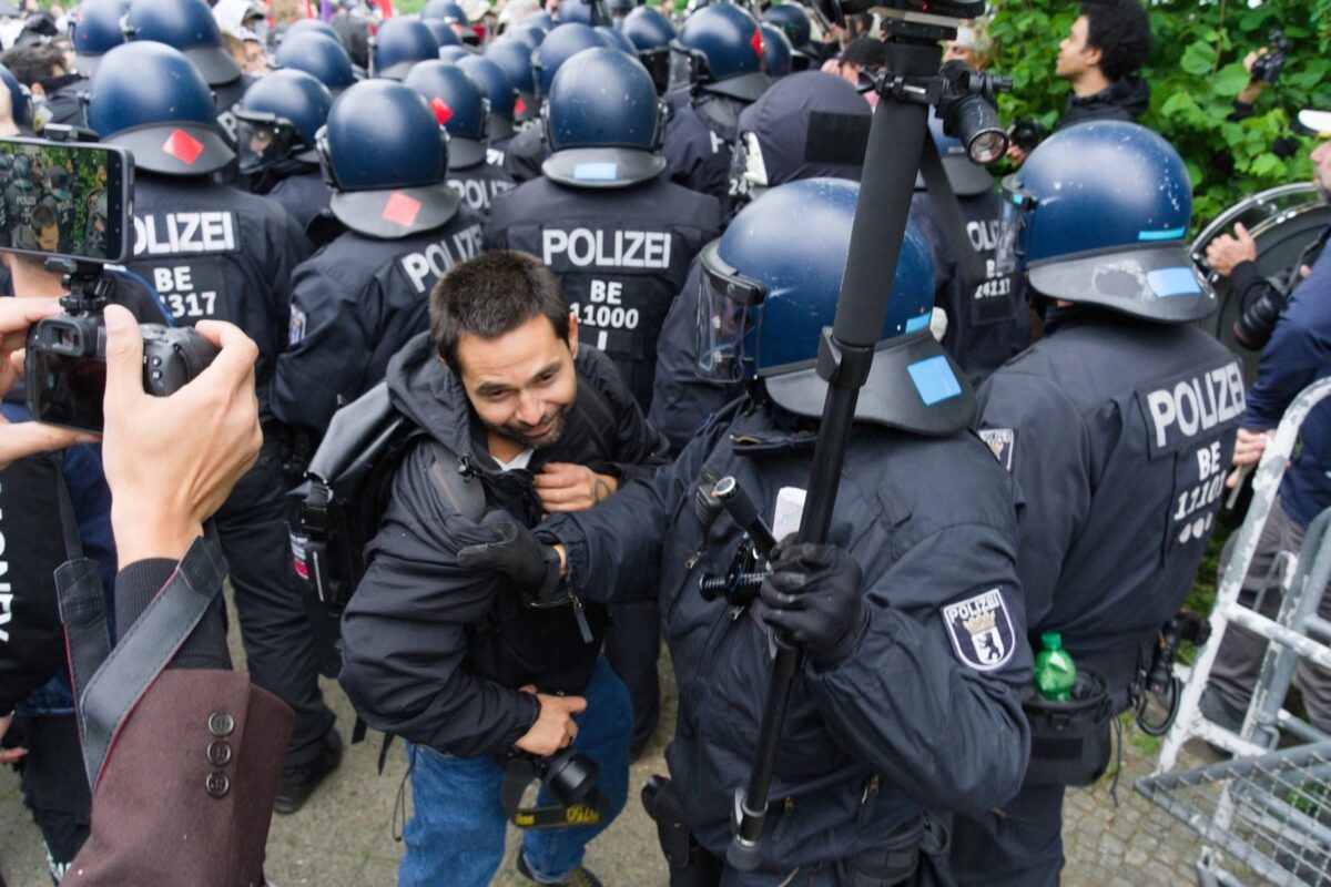 A journalist is grabbed by a police officer