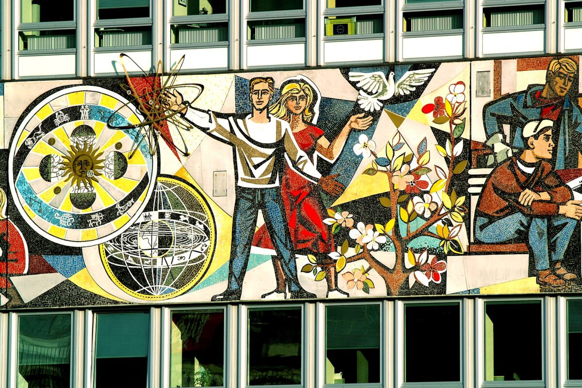 A mural depicting a socialist utopia: two smiling people with symbols of science and advancement swirling around them.