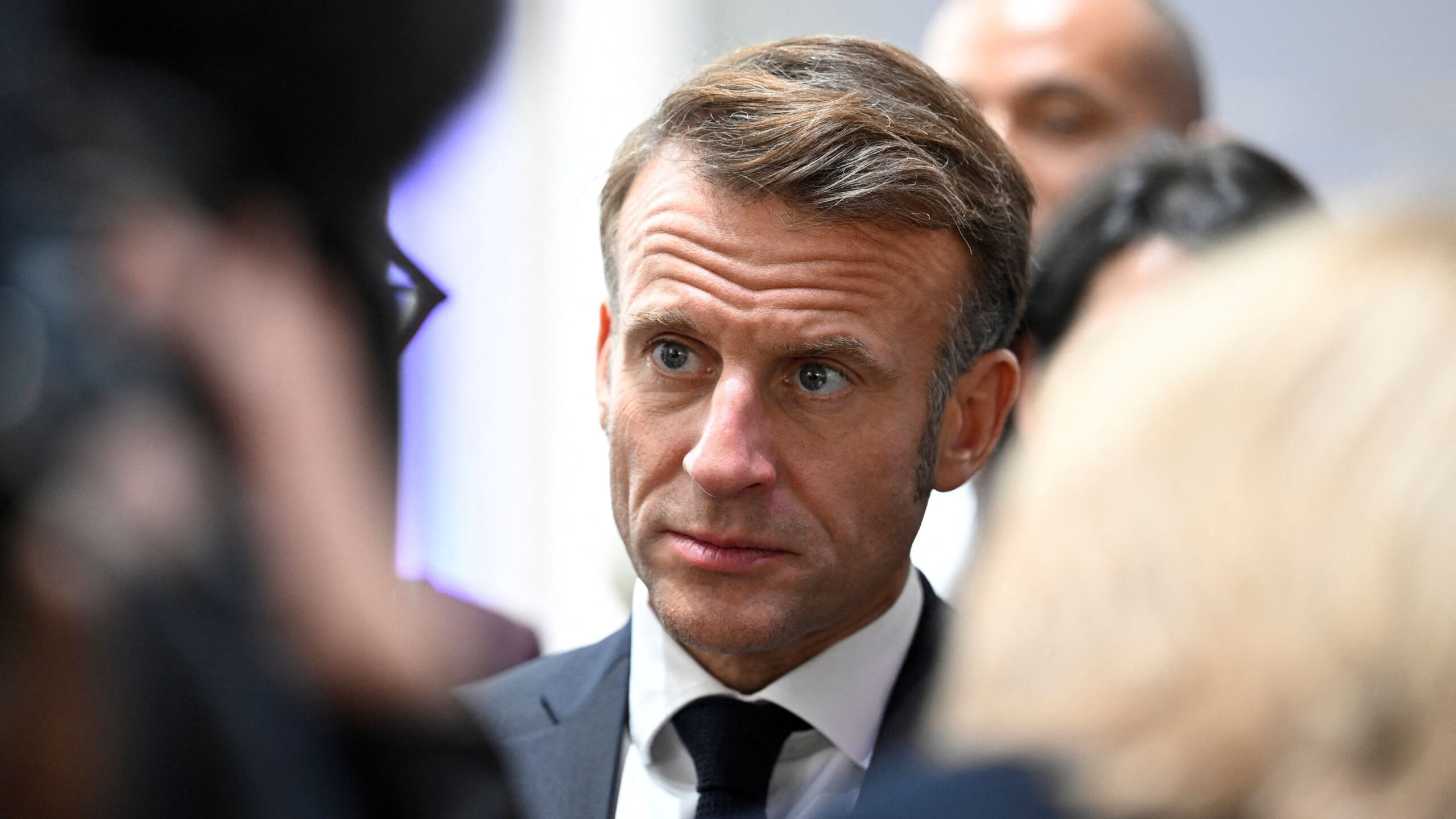 President Emmanuel Macron stares, seemingly concerned, through a crowd.