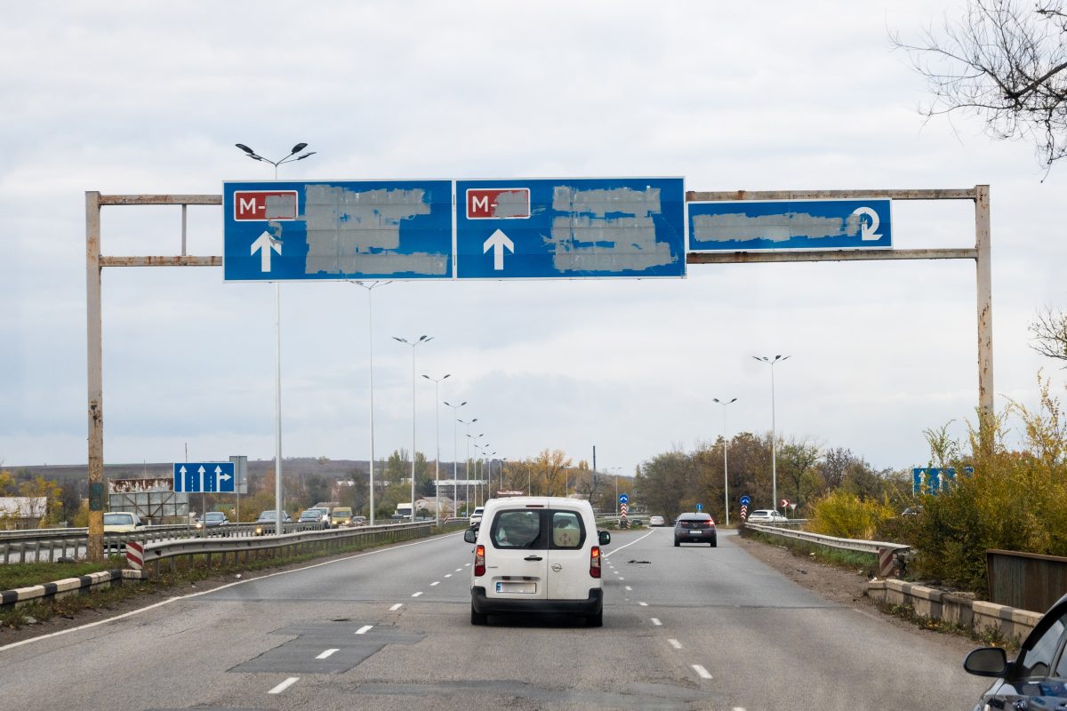 Van driving down an empty highway. The road signs have been painted over.