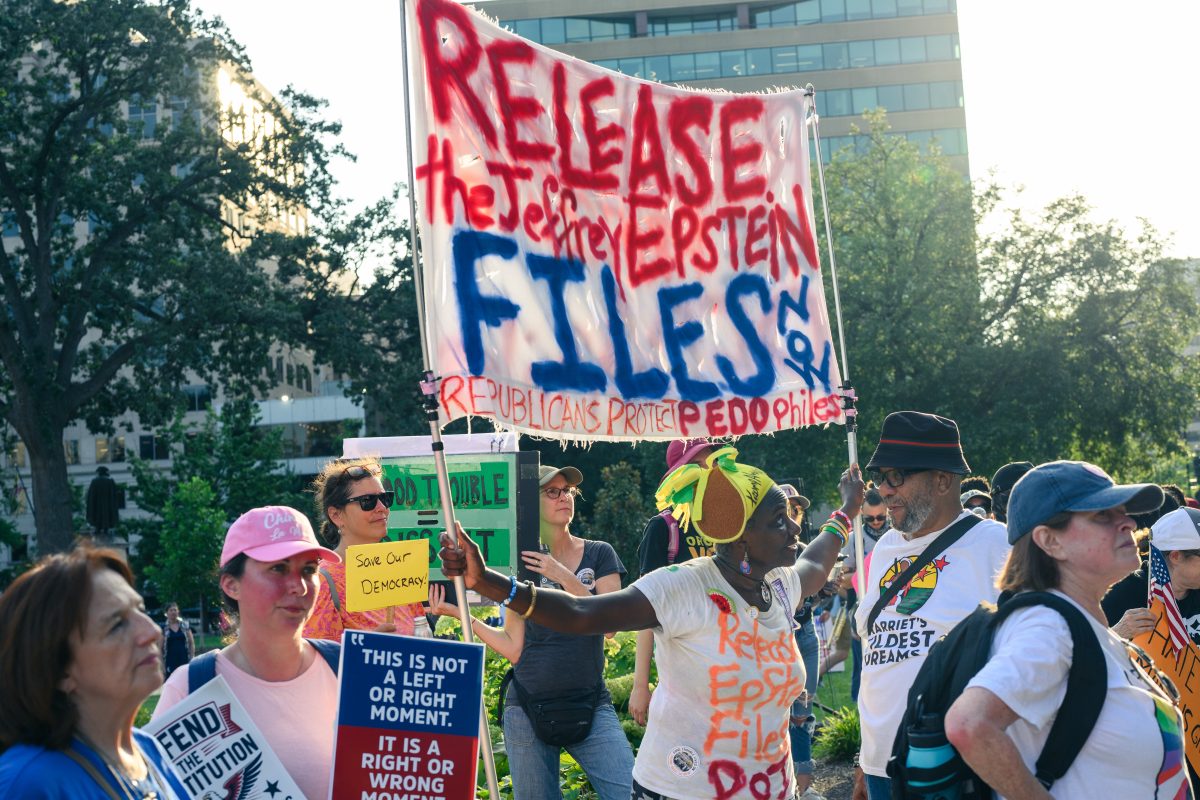 Protestors at the Good Trouble Protest in DC in 2025 celebrating the spirit of John Lewis, civil rights activist dating back to the 60s. One person holds up a huge banner with the words "Release the Jeffrey Epstein files NOW. Republicans support pedophiles." Another, in the foreground holds a small sign saying "This is not a left or right moment. It's a right or wrong moment."